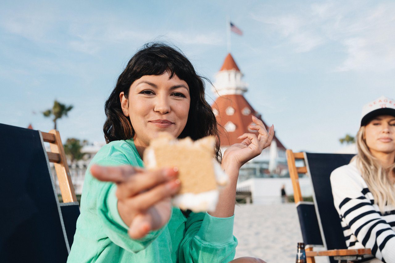 Woman holding up a s'more on the beach
