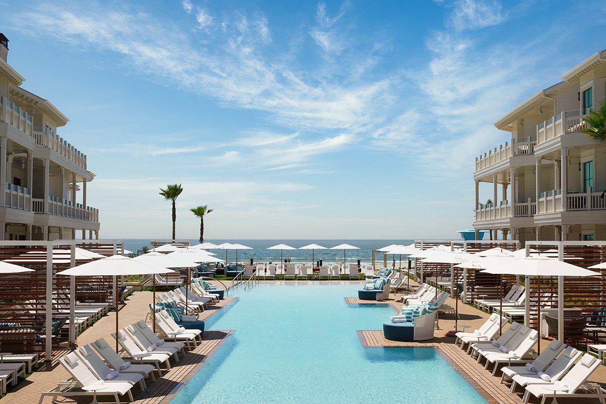 a blue sky above the pool surrounded by pool chairs