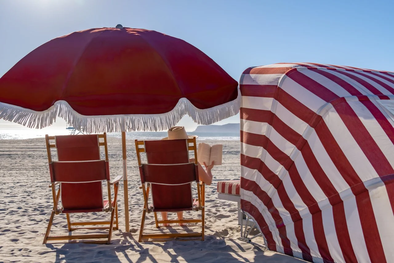 Woman reading a book under an umbrella on the beach
